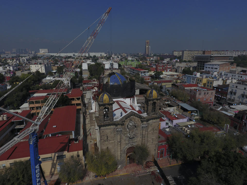 A crane lowers a steel arch into place overtop the damaged cupola, as part of a frame that will support a temporary metal roof, in the early stages of reconstruction work at Nuestra Senora de Los Angeles, or Our Lady of Angels church, three years after an earthquake collapsed nearly half of its 18th-century dome in Mexico City, Wednesday, Sept. 23, 2020. It is a titanic challenge: crumbling old stone and lime mortar walls and domes, without an ounce of cement or rebar, have to be built back with the same ancient materials. (AP Photo/Rebecca Blackwell)