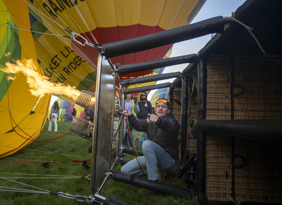 Pilot Kyle Laxton of Arizona directs a crew member to move a turn off a fan as he begins to light the burners on his balloon, which will carry some 13 passengers during the Albuquerque International Balloon Fiesta, Saturday, Oct. 7, 2023 in Albuquerque, N.M. (AP Photo/Roberto E. Rosales)