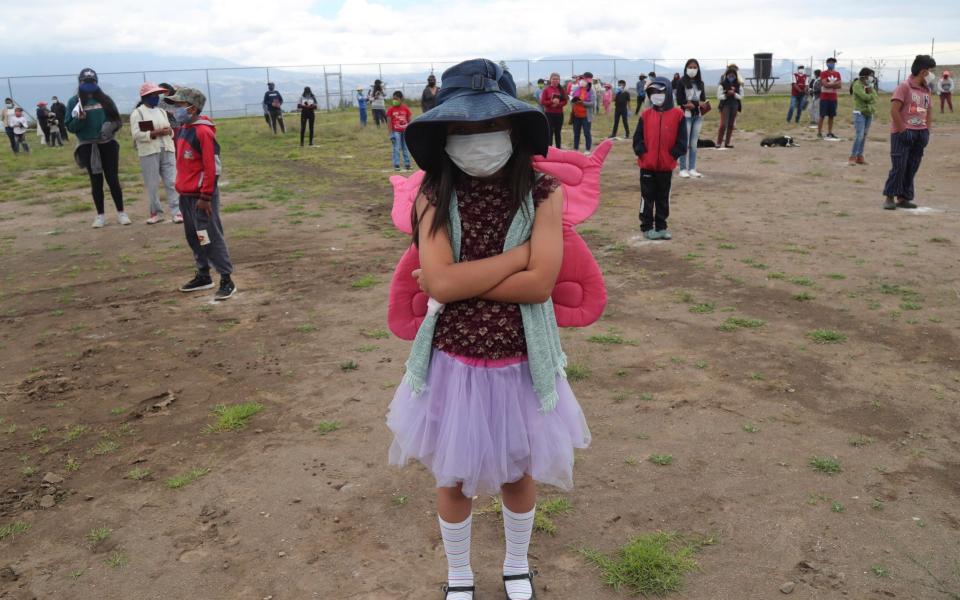 Children stand in a field keeping their distance waiting for a Children's Day gift, in Yaruqui near Quito, Ecuador - AP