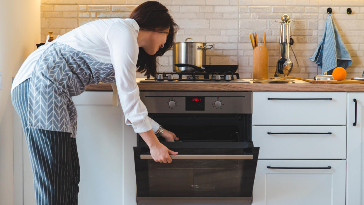  A woman leaning over to open an oven. 