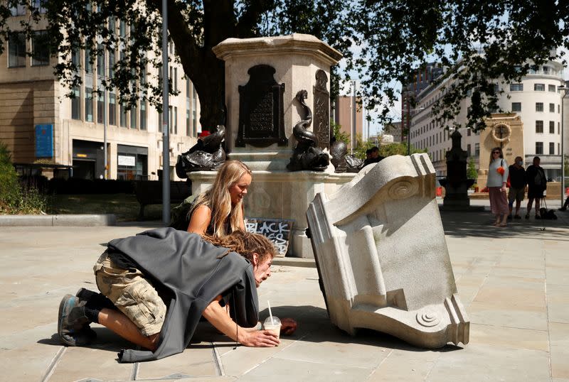 People observe the base of the statue of Edward Colston