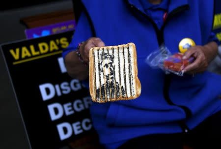 An abuse victim only known as Val holds up an artwork she created on a piece of toast, which she says depicts Australian Cardinal George Pell in a jail cell, outside the venue for Australia's Royal Commission into Institutional Response to Child Sexual Abuse in Sydney, Australia, March 1, 2016. REUTERS/David Gray