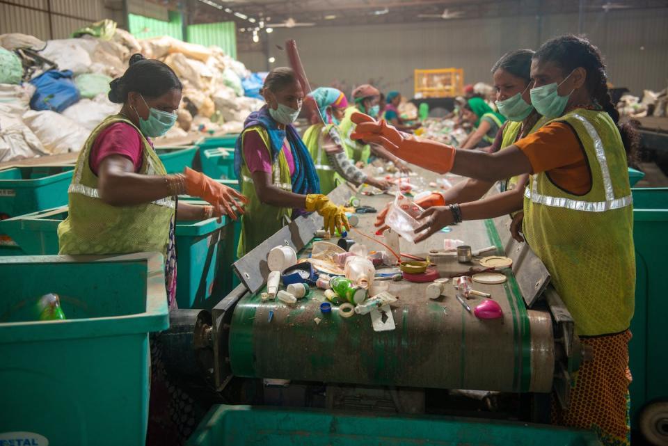 Waste workers separate paper and plastic on a conveyor belt in a recycling facility in New Delhi, India in September 2019. The ‘I Got Garbage’ digital platform turned the informal waste collection process into a formal process. (Shutterstock)