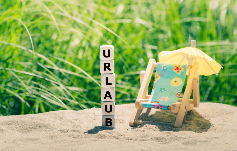 Dice form the German word "URLAUB" ("holiday" in English) next to a beach chair.