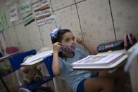 Rafaely de Melo se coloca la mascarilla durante una clase en la guardería Pereira Agustinho, un jardín de niños y preescolar, una vez que reanudó operaciones durante la pandemia del nuevo coronavirus en Duque de Caxias, Brasil, el lunes 6 de julio de 2020. La ciudad de Manaos en la Amazonía, y Duque de Caxias, en la región metropolitana de Río de Janeiro, se convirtieron el lunes en las primeras ciudades brasileñas en reanudar las clases presenciales en escuelas privadas desde que se desató la pandemia de COVID-19, según la federación de escuelas privadas del país. (AP Foto/Silvia Izquierdo)