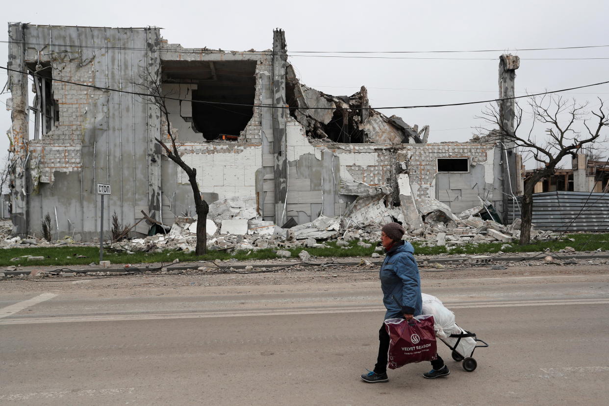 A person walks past a destroyed building in Mariupol.