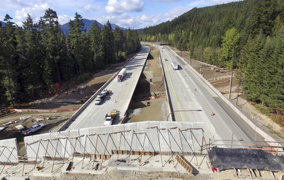 FILE - Interstate 90 traffic passes beneath a wildlife bridge under construction on Snoqualmie Pass, Wash., on Oct. 4, 2018. New Mexico will build its first wildlife highway overpasses for free-roaming cougars, black bears, bighorn sheep and other creatures large and small and will also set aside $100 million for conservation projects, under two bills signed Thursday, March 23, 2023. by Gov. Michelle Lujan Grisham. (AP Photo/Elaine Thompson)