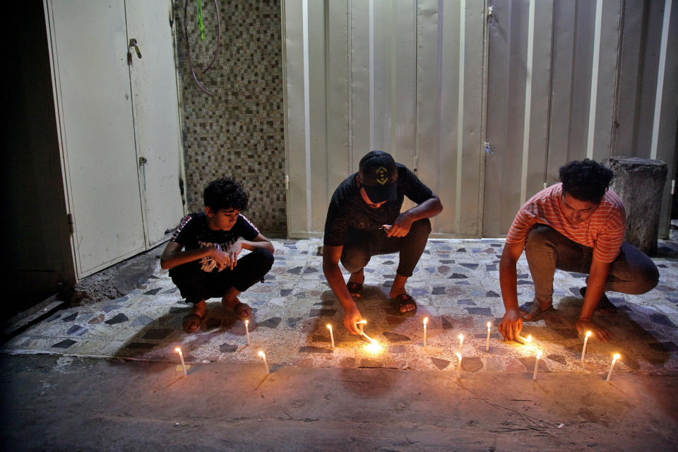 People light candles at the site of a bombing in Wahailat market in Sadr City, Iraq, Monday, July. 19, 2021. A roadside bomb attack targeted a Baghdad suburb Monday, killing at least 18 people and wounding dozens of others at a crowded market, Iraqi security officials said. (AP Photo/Khalid Mohammed)