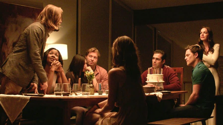 A group of people sit around a dinner table whilst two guests argue in The Invitation