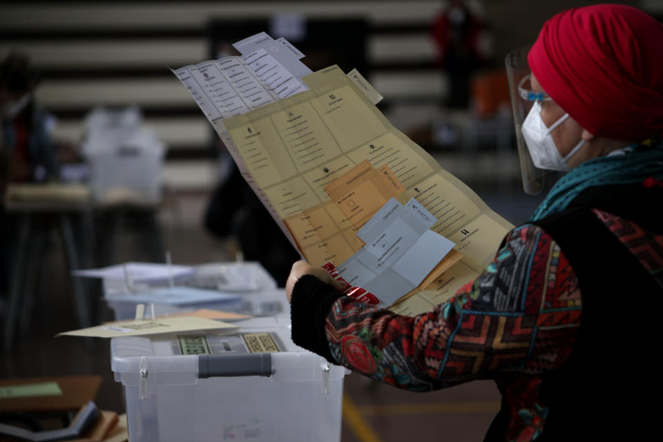 A voter carries her ballot during the Constitutional Convention election to select assembly members that will draft a new constitution, in Santiago, Chile, Saturday, May 15, 2021. The face of a new Chile begins taking shape this weekend as the South American country elects 155 people to draft a constitution to replace one that has governed it since being imposed during a military dictatorship. (AP Photo/Esteban Felix)