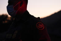 Border Patrol agent Justin Castrejon looks on near a section of new border structure Thursday, Sept. 24, 2020, near Tecate, Calif. President Donald Trump’s reshaping of U.S. immigration policy may be most felt in his undoing of asylum. Castrejon says migrants pay $8,000 to $10,000 to be guided through the mountains and picked up by a driver once they reach a road. (AP Photo/Gregory Bull)