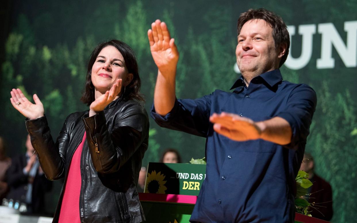 Annalena Baerbock in a pink t-shirt and leather jacket and her Green party co-leader Robert Habeck clap and celebrate during a national party convention - Bernd von Jutrczenka/dpa via AP