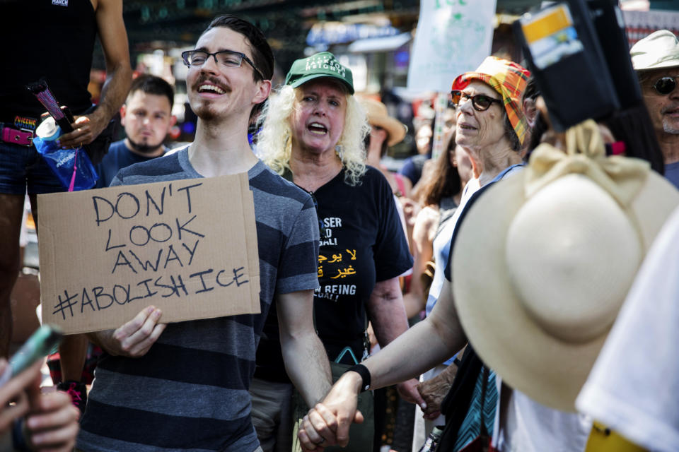 People holds hands as they chant at a rally before the start of a march in opposition to the Trump administration's plans to continue with raids to catch immigrants in the country illegally, Sunday, July 14, 2019, in the Queens borough of New York. (AP Photo/Julius Constantine Motal)