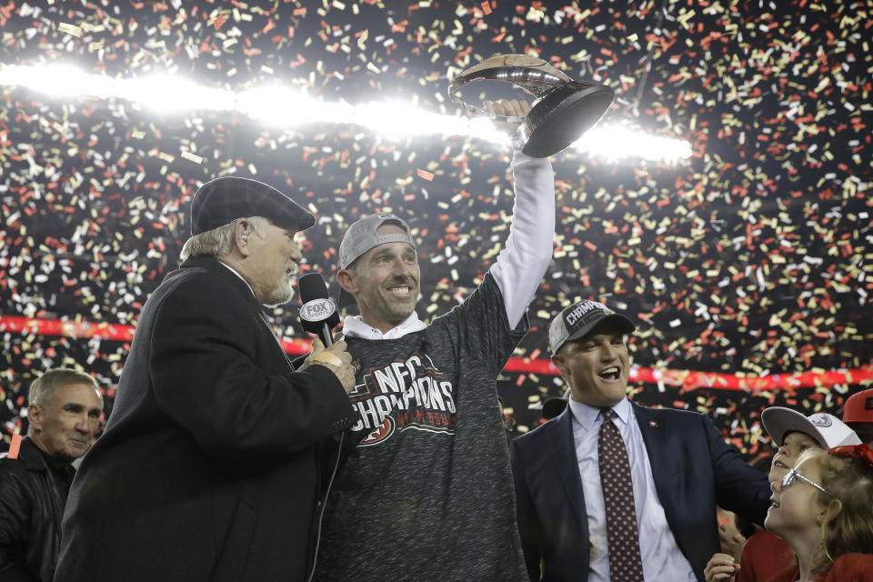 San Francisco 49ers head coach Kyle Shanahan, center, and general manager John Lynch, right, celebrate while interviewed by Terry Bradshaw after the NFL NFC Championship football game against the Green Bay Packers Sunday, Jan. 19, 2020, in Santa Clara, Calif. The 49ers won 37-20 to advance to Super Bowl 54 against the Kansas City Chiefs. Also pictured at bottom left is Mike Shanahan. (AP Photo/Marcio Jose Sanchez)