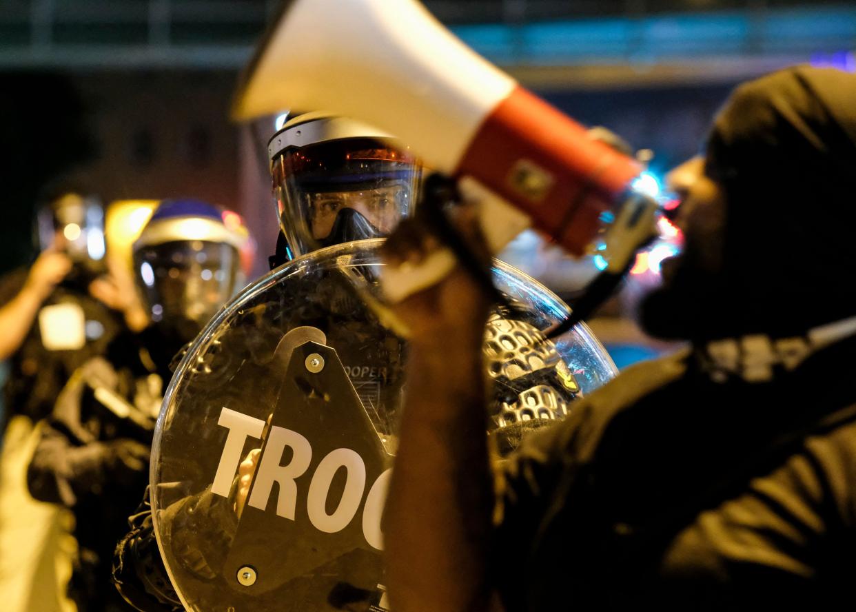 Troopers in riot gear watch as demonstrators gather outside Akron City Hall Sunday.