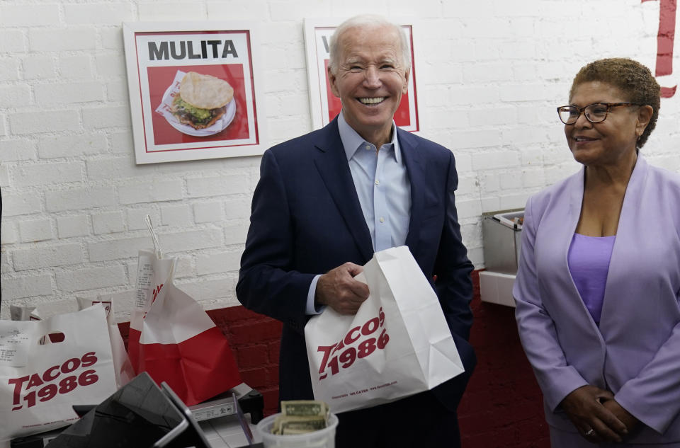 FILE - President Joe Biden, joined by Rep. Karen Bass, D, Calif., looks to members of the media after paying for a takeout order at Tacos 1986, a Mexican restaurant, in Los Angeles, Thursday, Oct. 13, 2022. (AP Photo/Carolyn Kaster, File)