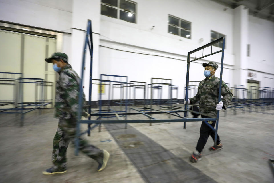 Soldiers build beds in a convention center that has been converted into a temporary hospital in Wuhan in central China's Hubei Province, Tuesday, Feb. 4, 2020. China said Tuesday the number of infections from a new virus surpassed 20,000 as medical workers and patients arrived at a new hospital and President Xi Jinping said "we have launched a people's war of prevention of the epidemic." (Chinatopix via AP)