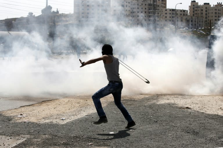 A Palestinian protester uses a slingshot to throw stones towards Israeli security forces during clashes near the Jewish West Bank settlement Beit El, north of Ramallah on October 5, 2015