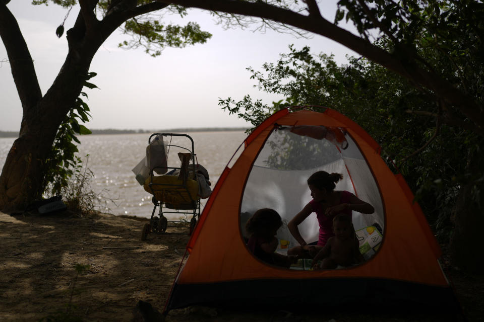 Venezuelan migrant Eliannis Gonzalez rests with her children in a tent near the Branco River in Boa Vista, Roraima state, Brazil, Friday, April 7, 2023. (AP Photo/Matias Delacroix)