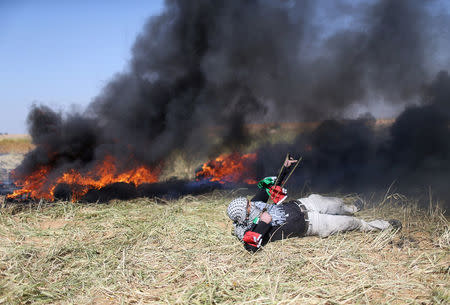 A Palestinian hurls stones at Israeli troops during clashes at the Gaza-Israel border at a protest demanding the right to return to their homeland, in the southern Gaza Strip March 31, 2018. REUTERS/Ibraheem Abu Mustafa