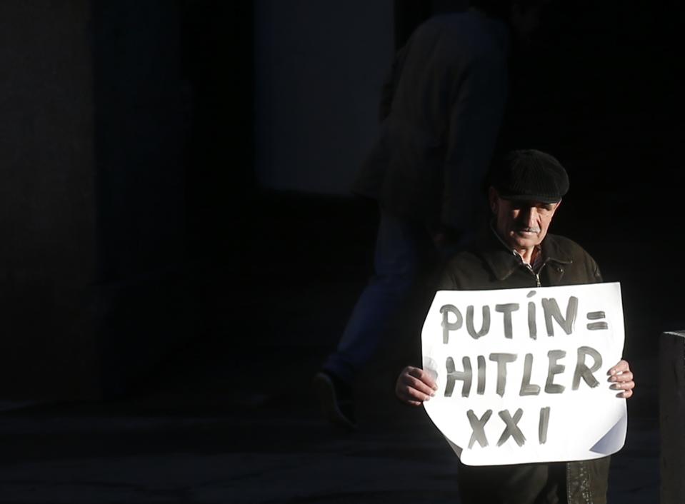 A protestor holds a banner against Russian President Vladimir Putin in front of the foreign ministry in Madrid before a meeting between Foreign Minister Lavrov and Spanish counterpart Garcia-Margallo