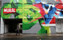 BRISTOL, ENGLAND - AUGUST 17: A woman walks in front of part of the 'See No Evil' street art project at Nelson Street on August 17, 2012 in Bristol, England. The project, now in its second year, is Europe's biggest street art festival and has attracted top graffiti artists from all over the world. Organizers hope it will continue to be a draw for tourists visiting Bristol, often seen the spiritual home of underground artist Banksy. (Photo by Matt Cardy/Getty Images)