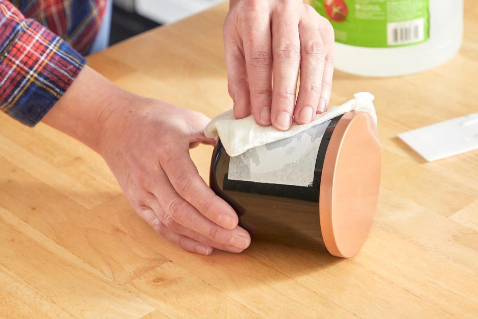 Woman uses vinegar to remove adhesive label from a jar.