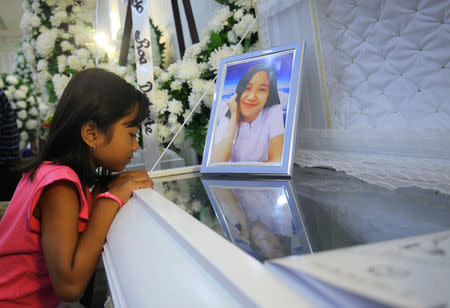 A girl looks at the coffin of her aunt, a call centre worker who was killed during a fire at a mall in Davao city in the Philippines, December 27, 2017. REUTERS/Lean Daval Jr