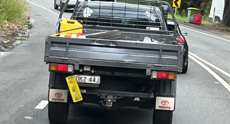 A ute driving on an Australian road with two number plates.