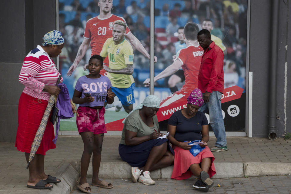 Customers place their bets outside a sports betting shop in the Soweto township of Johannesburg, South Africa, Thursday, Dec. 8, 2022. Although sports betting is a global phenomenon and a legitimate business in many countries, the stakes are high on the continent of 1.3 billion people because of lax or non-existent regulation, poverty and widespread unemployment. (AP Photo/Denis Farrell)