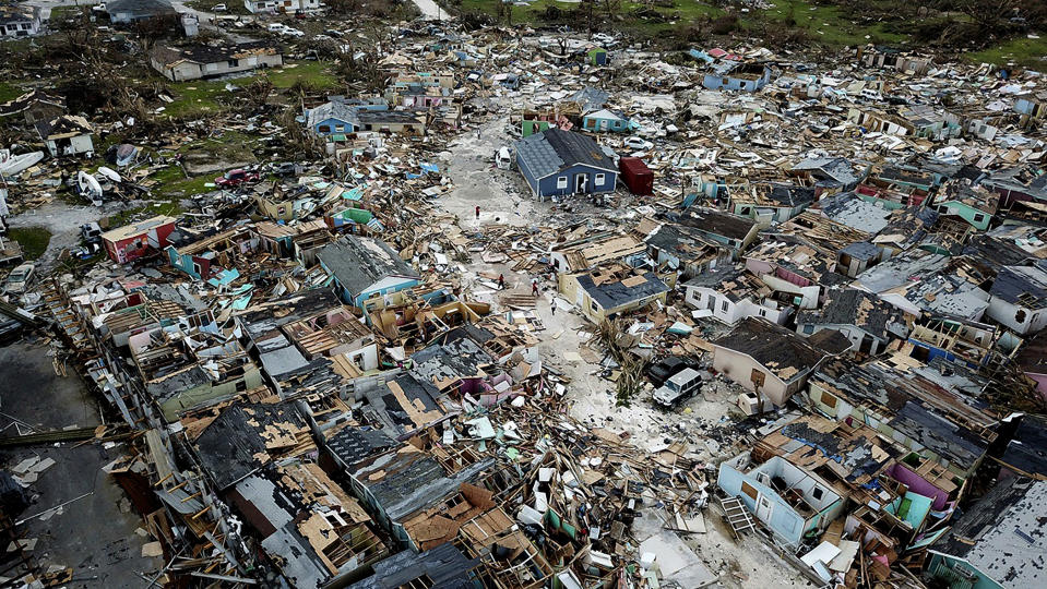 People walk through a neighborhood destroyed by Hurricane Dorian at Marsh Harbour in Great Abaco Island, Bahamas on Thursday, Sept. 5, 2019. (Al Diaz/Miami Herald via AP)