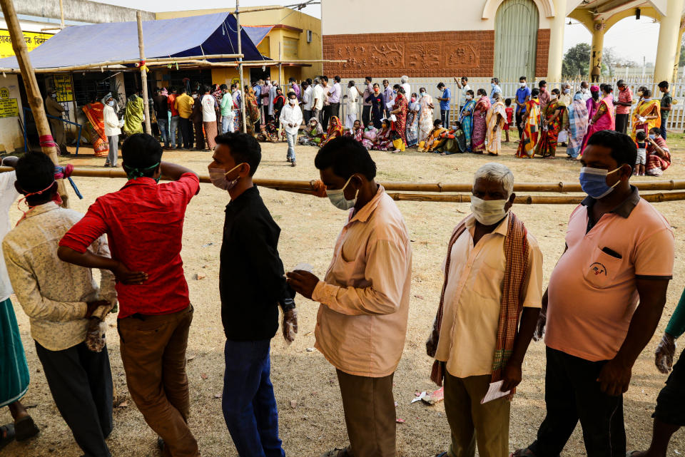 Voters stand in queues to cast their votes outside a polling booth during first phase of elections in West Bengal state in Medinipur, India, Saturday, March 27, 2021. Voting began Saturday in two key Indian states with sizeable minority Muslim populations posing a tough test for Prime Minister Narendra Modi’s popularity amid a months-long farmers’ protest and the economy plunging with millions of people losing jobs because of the coronavirus pandemic. (AP Photo/Bikas Das)