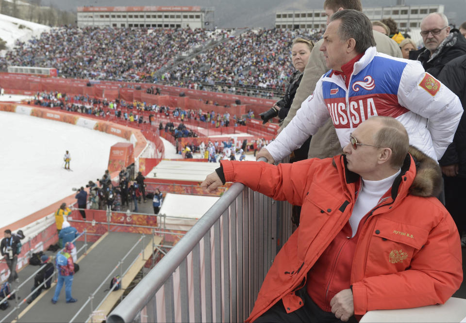 FILE - Russian President Vladimir Putin, foreground, watches downhill ski competition of the 2014 Winter Paralympics in Roza Khutor mountain district of Sochi, Russia, as Russia's sports minister Vitaly Mutko stands behind on March 8, 2014. Putin opens the Winter Olympics in Sochi, a costly prestige project that he was instrumental in winning for Russia. (Alexei Nikolsky, Sputnik, Kremlin Pool Photo via , File)