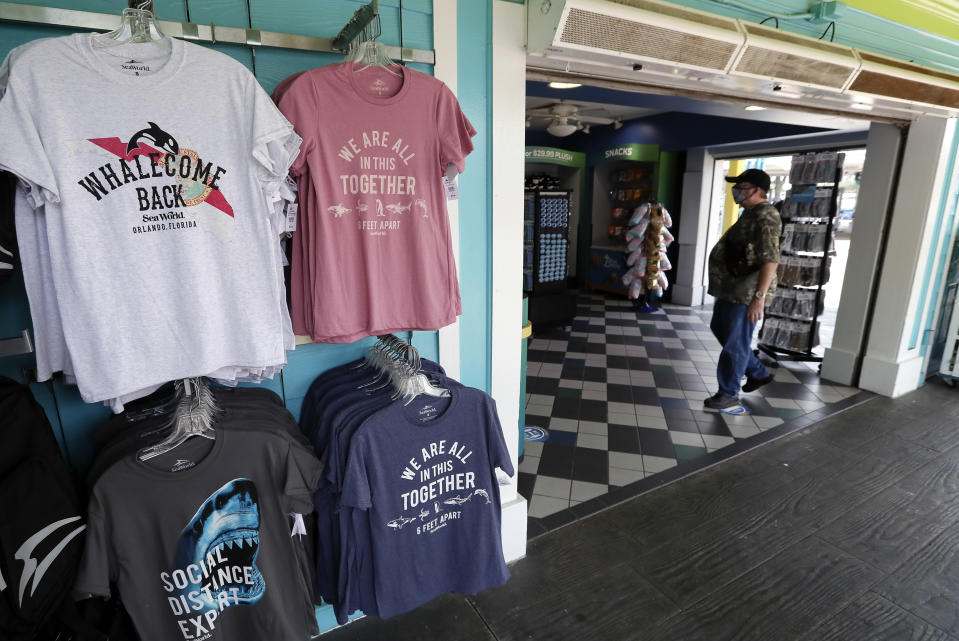 T-Shirts with social distancing sayings are on sale at SeaWorld as it reopened with new safety measures in place Thursday, June 11, 2020, in Orlando, Fla. The park had been closed since mid-March to stop the spread of the new coronavirus. (AP Photo/John Raoux)