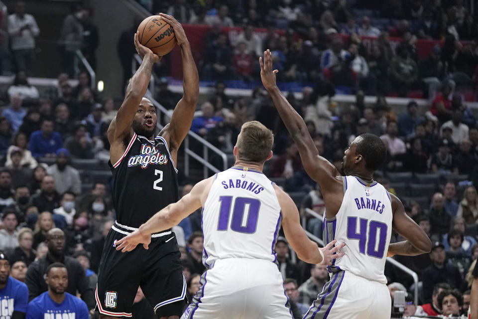 Los Angeles Clippers forward Kawhi Leonard, left, shoots as Sacramento Kings forward Domantas Sabonis, center, and forward Harrison Barnes defend during the first half of an NBA basketball game Friday, Feb. 24, 2023, in Los Angeles. (AP Photo/Mark J. Terrill)