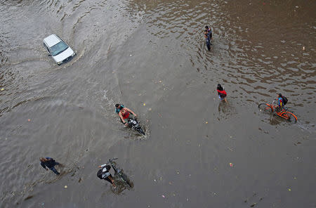 FILE PHOTO: People wade through a flooded road after heavy rains in Ahmedabad, India, June 24, 2018. REUTERS/Amit Dave/File photo