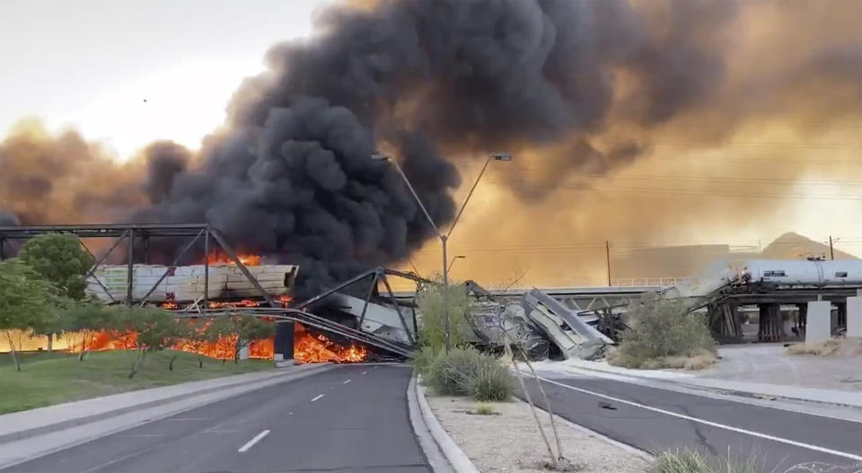 Smoke fills the sky at the scene of a train derailment in Tempe, Ariz., on Wednesday, July 29, 2020. Officials say a freight train traveling on a bridge that spans a lake in the Phoenix suburb derailed and set the bridge ablaze and partially collapsing the structure. There were no immediate reports of any leaks. (Daniel Coronado via AP)