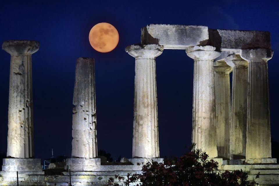 June's full moon, known as the Strawberry Moon, rises above the Apollo Temple in ancient Corinth, on June 17, 2019.