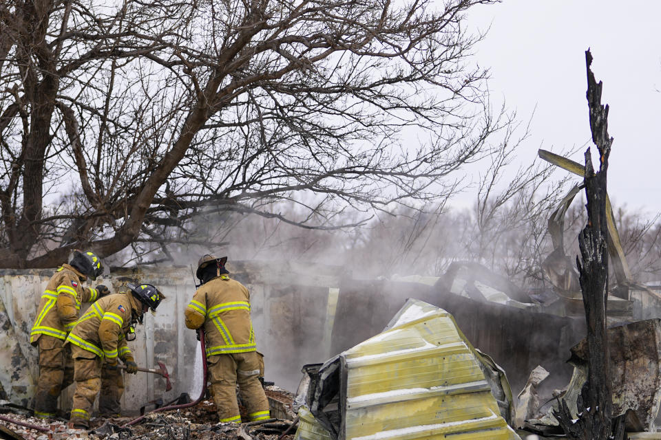 Fire officials from Lubbock, Texas, help put out smoldering debris of a home destroyed by the Smokehouse Creek Fire, Thursday, Feb. 29, 2024, in Stinnett, Texas. (AP Photo/Julio Cortez)
