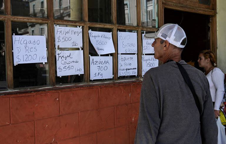 People look at food prices at a private business in Havana on December 20, 2023. Cuba's economy will shrink by up to 2% this year, Finance Minister Alejandro Gil estimated on Wednesday, after acknowledging that the country will not be able to achieve the projected economic growth of 3% by 2023. (Photo by YAMIL LAGE / AFP)