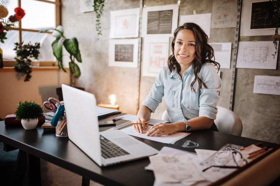 Beautiful business woman sitting in the office, looking at camera and smiling