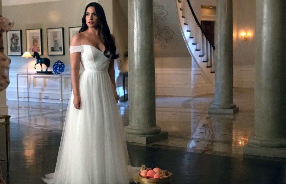 she's in character, standing in a large house wearing a wedding dress