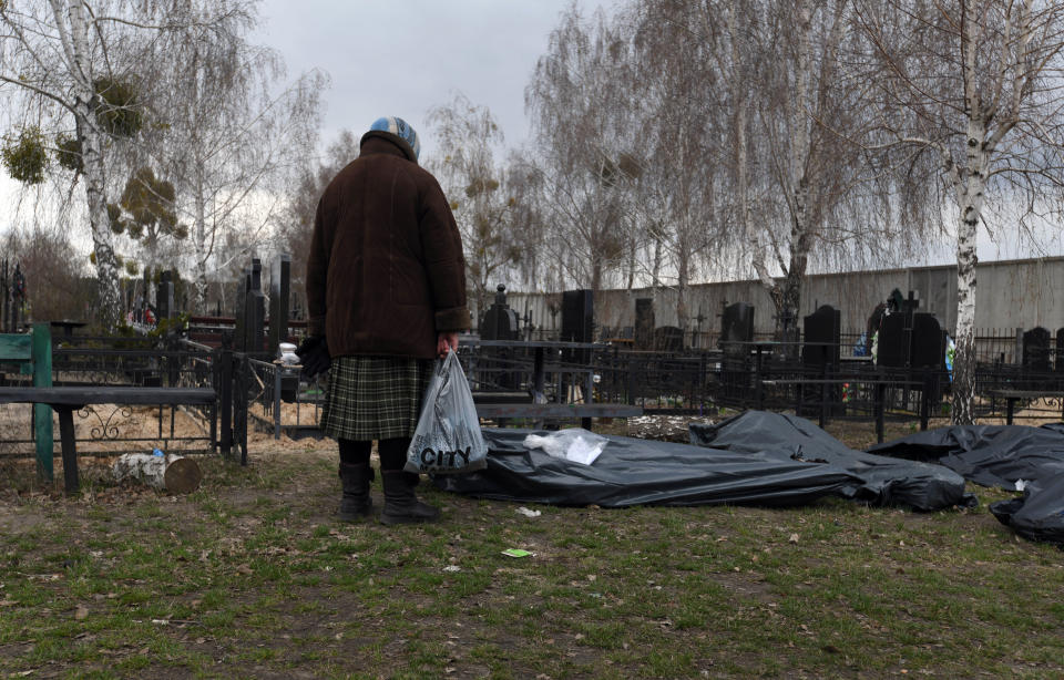 A woman stands over the body of her son as collectors move bodies to the city morgue in Bucha on April 12.