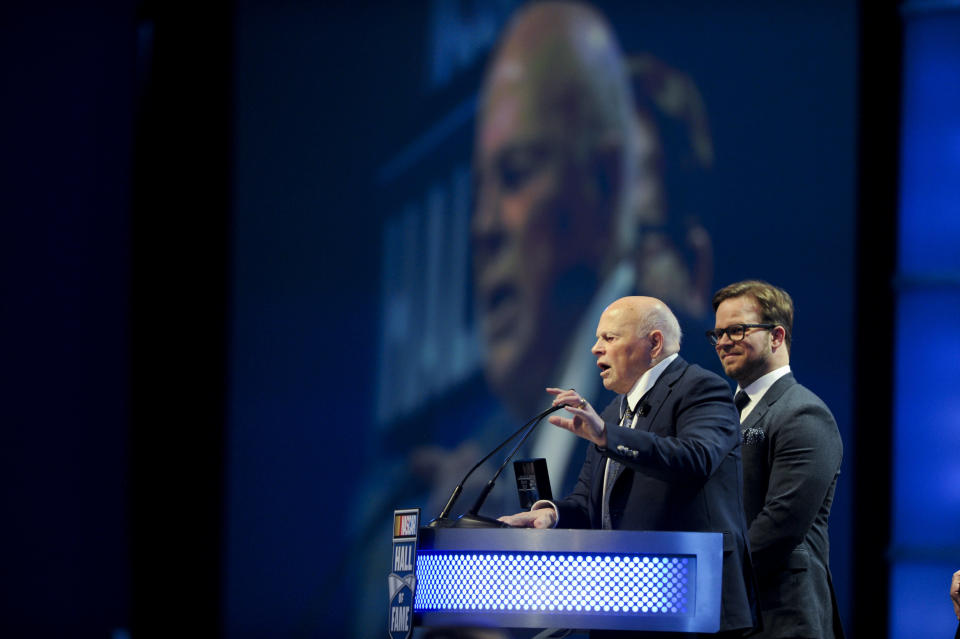 Inductee, Bruton Smith, left, entertains the crowd as his son, Marcus Smith looks on during the NASCAR Hall of Fame Induction ceremony in Charlotte, N.C., Saturday, Jan. 23, 2016. (AP Photo/Mike McCarn)