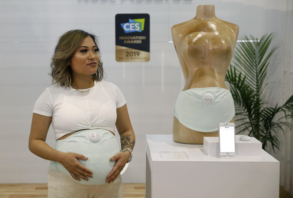 Mary Mendiola wears the Owlet Band pregnancy monitor at the Owlet booth at CES International, Wednesday, Jan. 9, 2019, in Las Vegas. The device can track fetal heart rate, kicks and contractions. (AP Photo/John Locher)