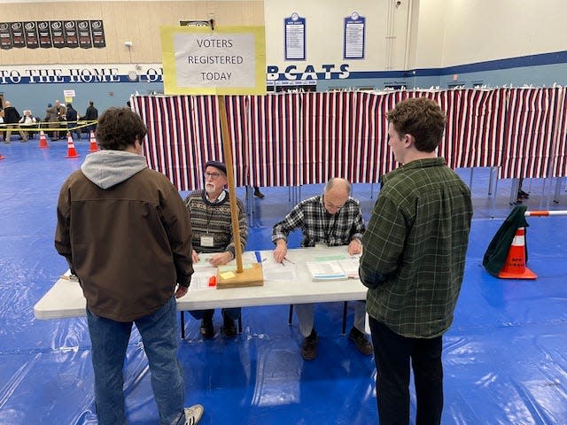 Ballot clerks Bill deVries, left, and Mike Watson check in voters at the New Hampshire primary polls in Durham at Oyster River High School Tuesday, Jan. 23, 2024.