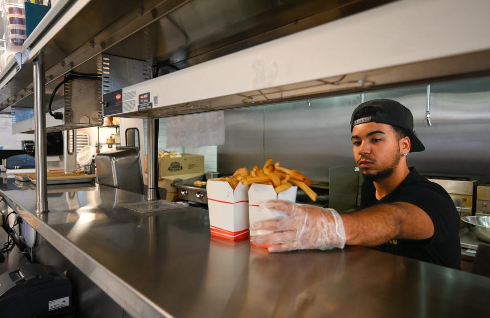 Cook Omar Hernandez places an order of french fries in the window at Flip the Bird in Salem, Massachusetts, on July 14, 2022.