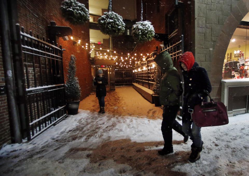 Pedestrians walk as snow falls in Harvard Square in Cambridge, Mass. Tuesday, Jan. 21, 2014. Heavy snow has been forecast and a blizzard warning was posted for portions of Massachusetts. (AP Photo/Elise Amendola)