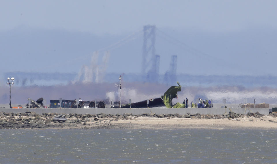 The tail of Asiana Flight 214, which crashed on Saturday, July 6, 2013, is seen in front of a span of the Bay Bridge on a tarmac at San Francisco International Airport in San Francisco, Wednesday, July 10, 2013. Investigators are struggling to piece together what went wrong in an accident that left two of the 307 aboard dead and close to 20 seriously injured. (AP Photo/Jeff Chiu)