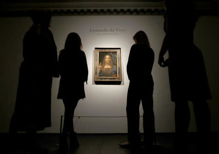 FILE PHOTO: Members of Christie's staff pose for pictures next to Leonardo da Vinci's "Salvator Mundi" painting in London, October 24, 2017. REUTERS/Peter Nicholls/File Photo